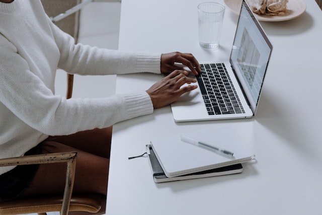 person in white shirt typing on their laptop at their desk